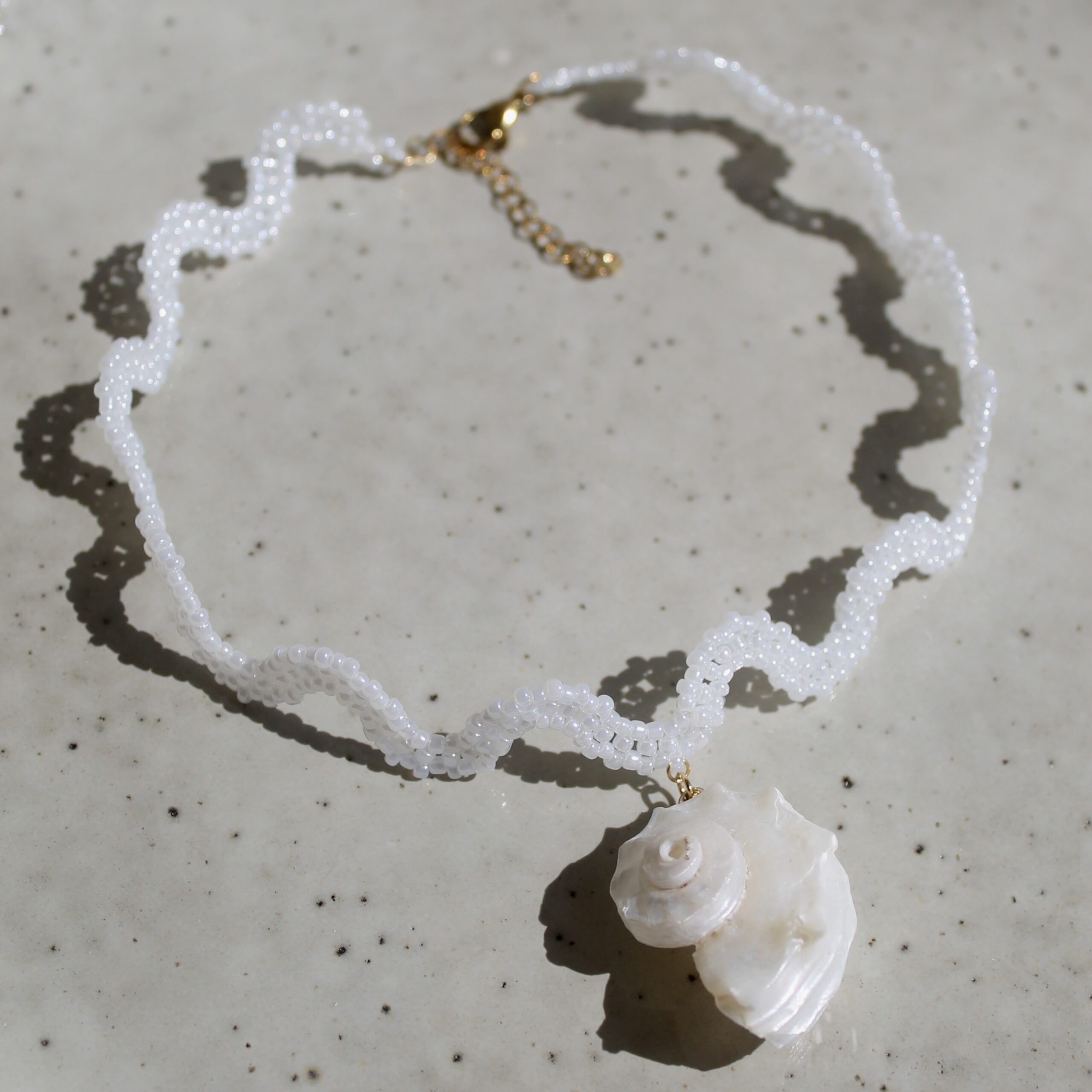 Wavy shell choker with spiral shell pendant